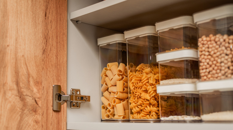 A pantry organized with dry food in matching canisters.