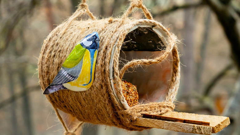 A jar on its side, wrapped in twine and full of bird seed