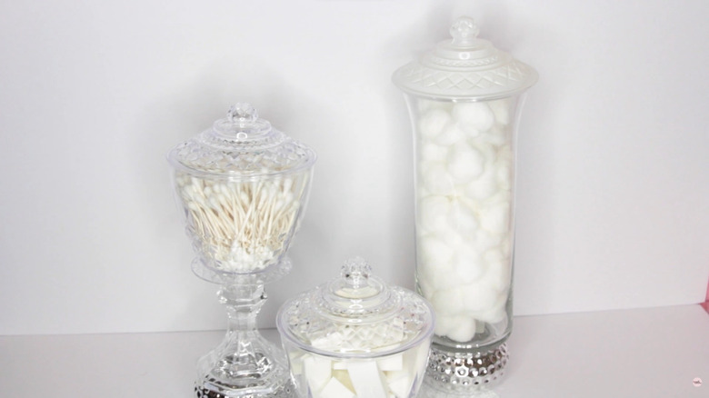 DIY glass vases with lids stocked with bathroom sponges, Q-tips, and cotton balls