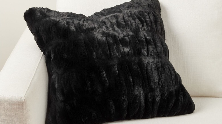 Comfy black fur throw pillow on all-white modern classic couch