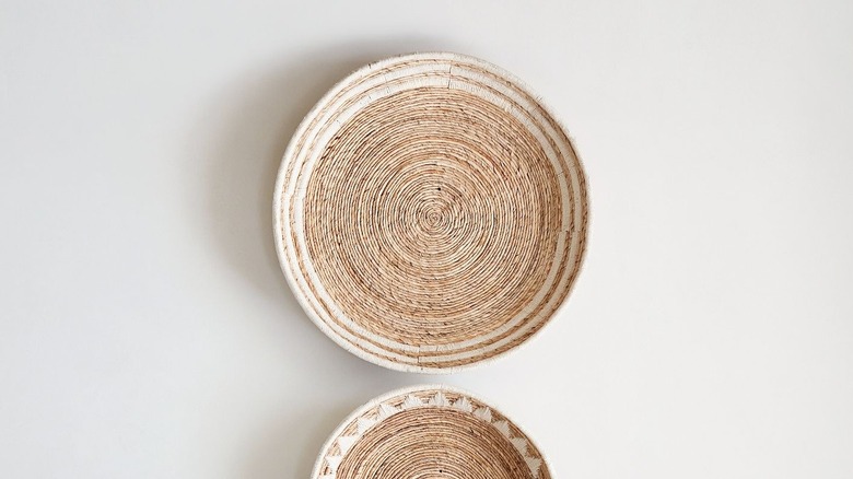 Woven basket with white rope accent on white wall above other basket