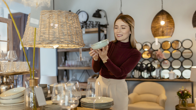 Young woman checking price in luxury home decor store like Pottery Barn