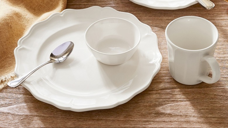 White plates with scalloped edges and a glossy finish on rustic wood table