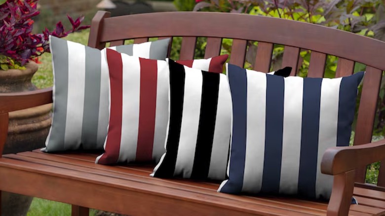 Four striped porch pillows sit on a wooden bench