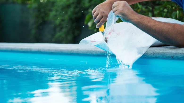 Person pouring salt into swimming pool