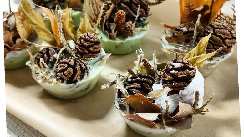 Pinecones, wicks, and leaves lodged in reused candle wax