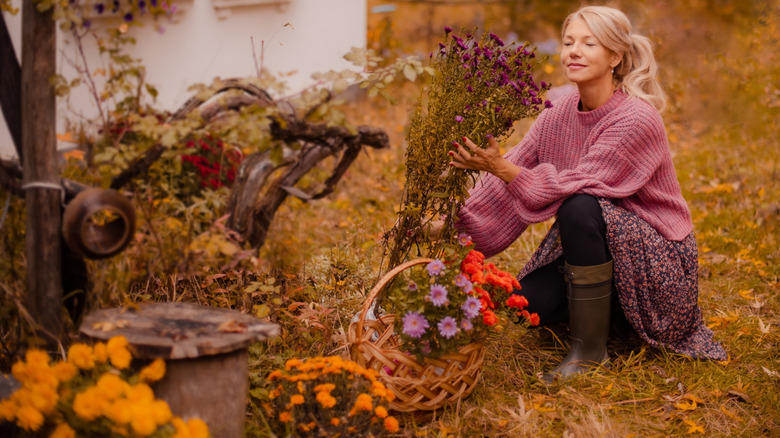 A woman smiles as she tends to a fall garden of mums and marigolds