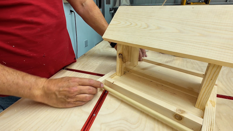 Person standing beside a simple bird feeder that can be made of scrap wood