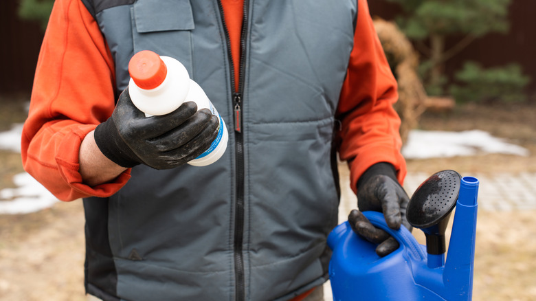 Person reading bottle of chemical fertilzer
