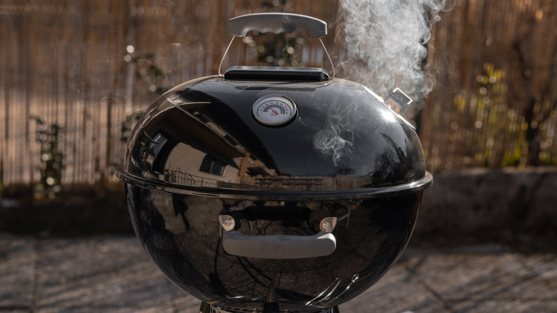 Smoke pours out of a black pellet grill