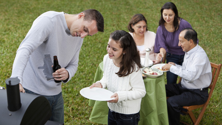 A family having a barbeque holding paper plates