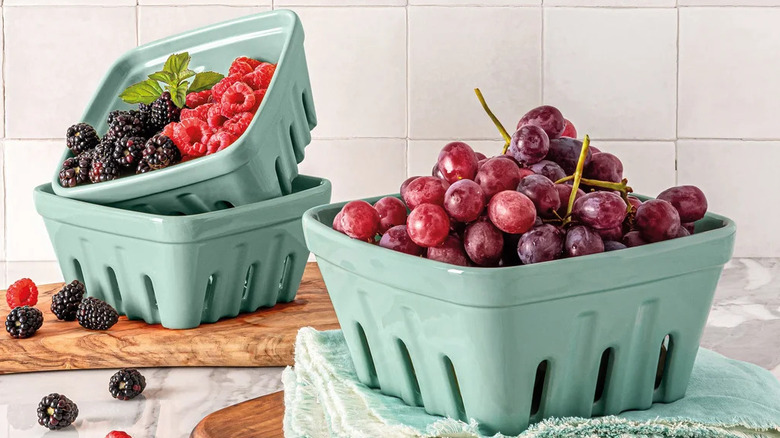 Three teal ceramic berry baskets hold fruit on a kitchen counter