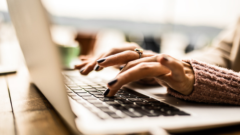 A woman's hands are shown using a laptop