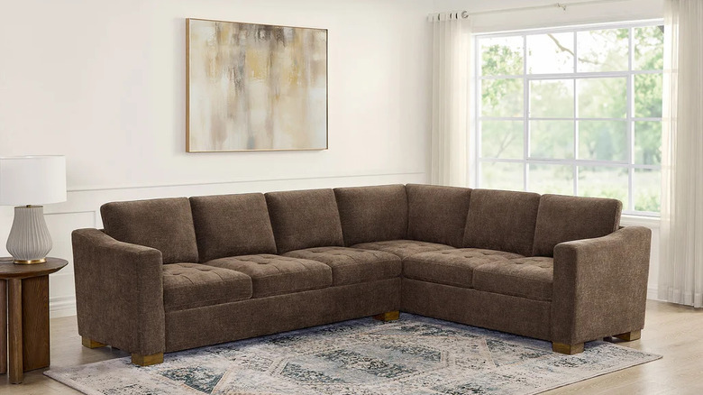 A large brown sectional sits in front of a living room window