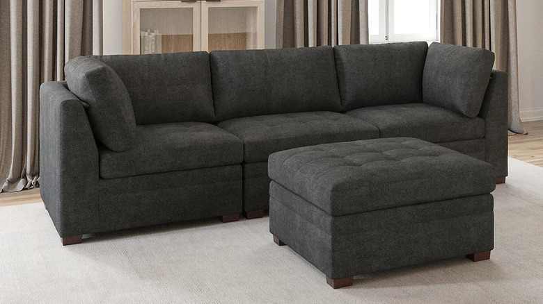 A dark gray ottoman sits in front of a matching three-seat sofa