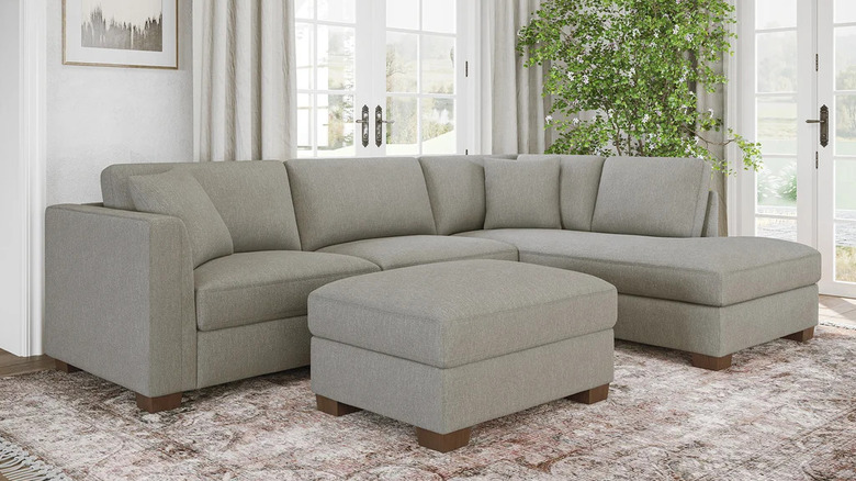 A greige sectional sofa with chaise sits near two sets of French doors