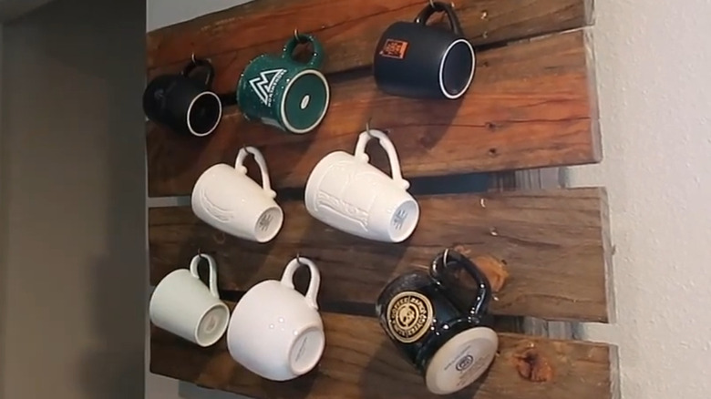 Coffee mugs hanging on reclaimed wood wall display