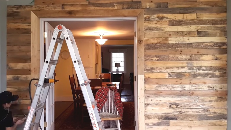 Woman building accent wall made of deconstructed pallet wood pieces
