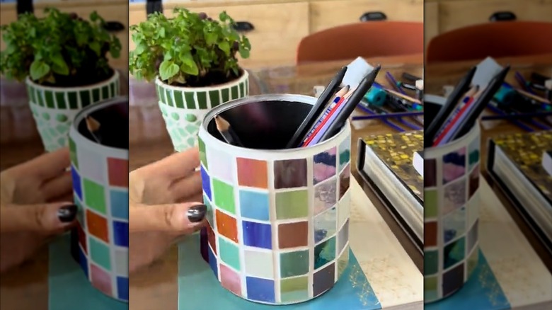 Woman placing DIY mosaic pencil holder made from coffee tin and crafting tiles