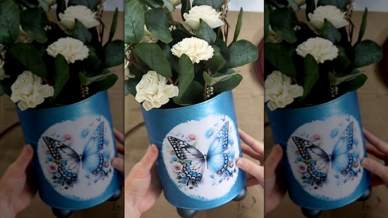 Blue butterfly planter with white carnations made from old coffee canister