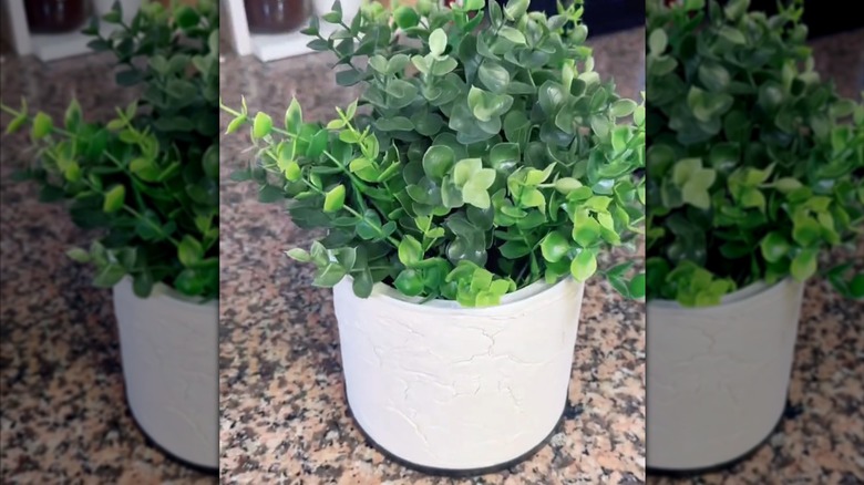 Modern white planter made from coffee container with artificial plant on granite countertop