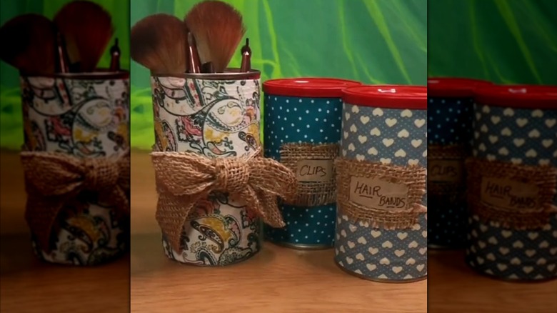 Repurposed narrow coffee tins with burlap accessories being used as cosmetic organizers on wood table