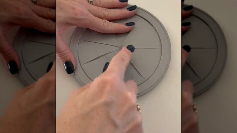 Woman with black nail polish slicing coffee can lid for DIY bag holder