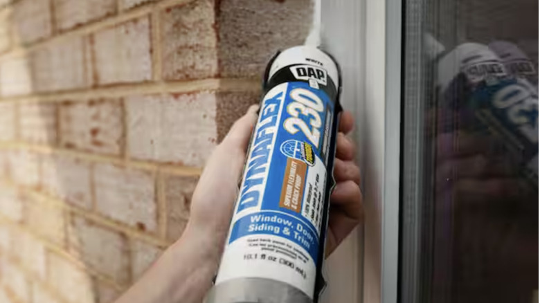 Man using caulking to seal around windows