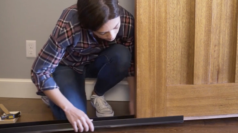Woman adding new door seal to front door