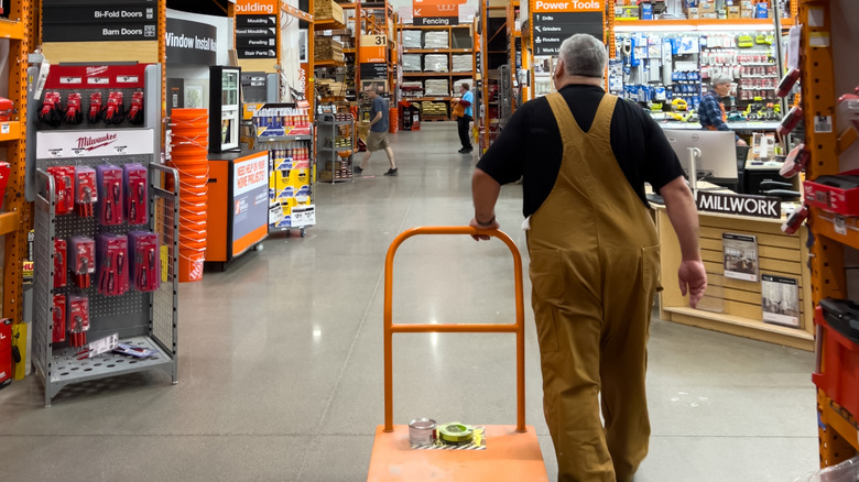 A man pulls a lumber cart through the aisles of Home Depot