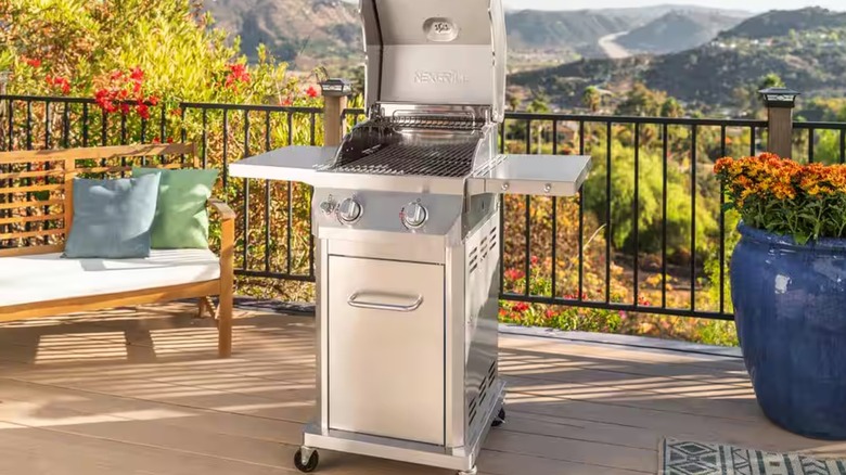 A small stainless steel grill sits on a wrought-iron fenced patio overlooking the mountains