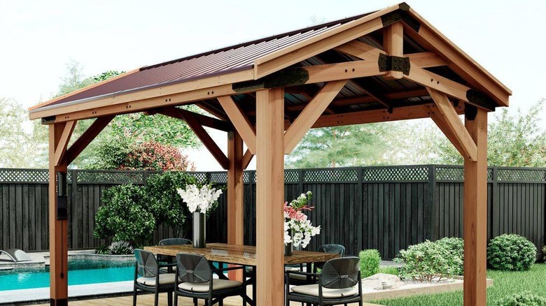 A Backyard Discovery Norwood cedar gazebo outside with a table and chairs underneath its roof
