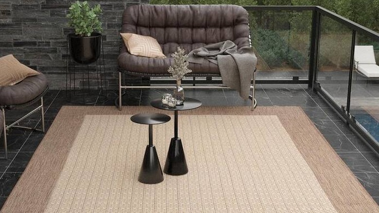 A Couristan Recife checkered field tan-brown solid indoor/outdoor area rug on a patio floor