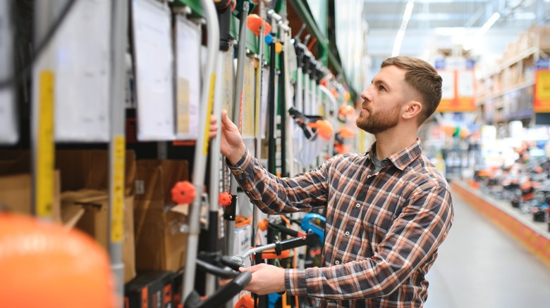 Man looking at trimmers in lawn section of Home Depot