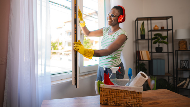 Woman opening a window while cleaning