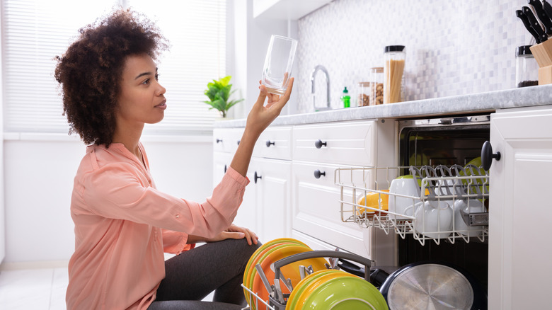 Woman inspecting a glass from full dishwasher