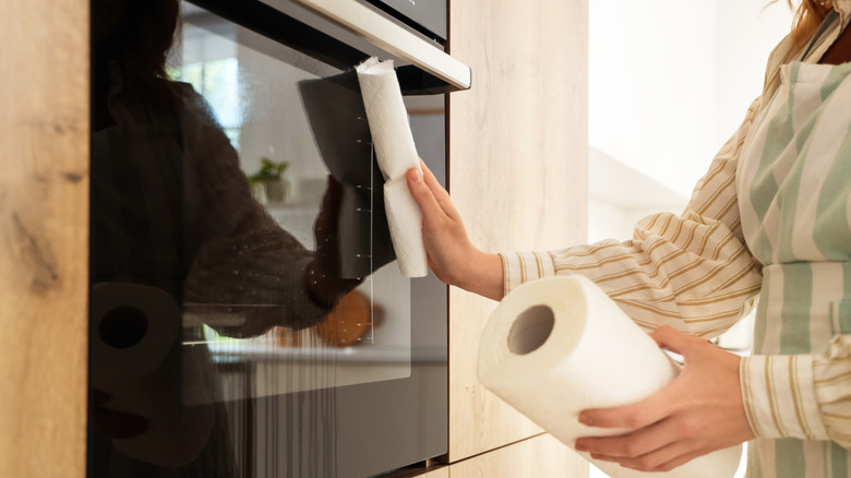 Person holding a roll of paper towels while cleaning oven