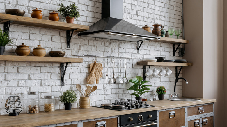 A mounted pot rack over a stove alongside floating shelves
