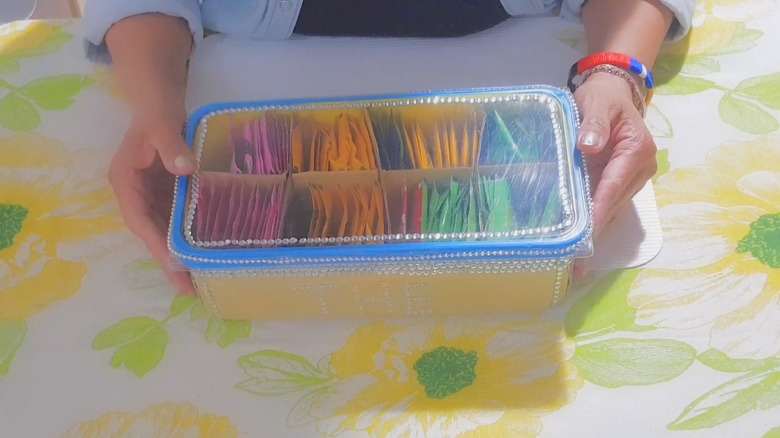 Woman holding plastic mop wipe container with organized teabags
