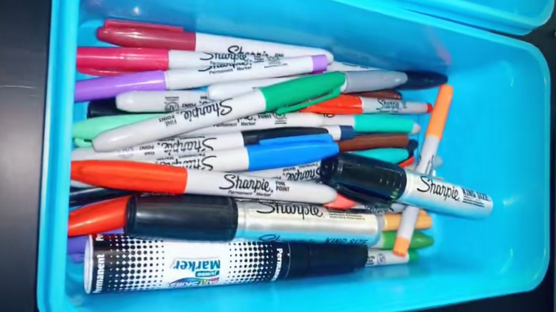 Colored permanent markers cluttered in a Swiffer container