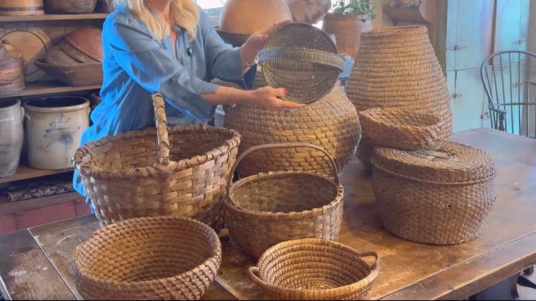 Woman going through massive small and large woven basket collection on wood table