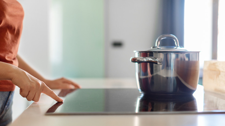 A person turning on a glass cooktop