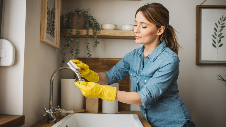 Woman cleaning a kitchen faucet
