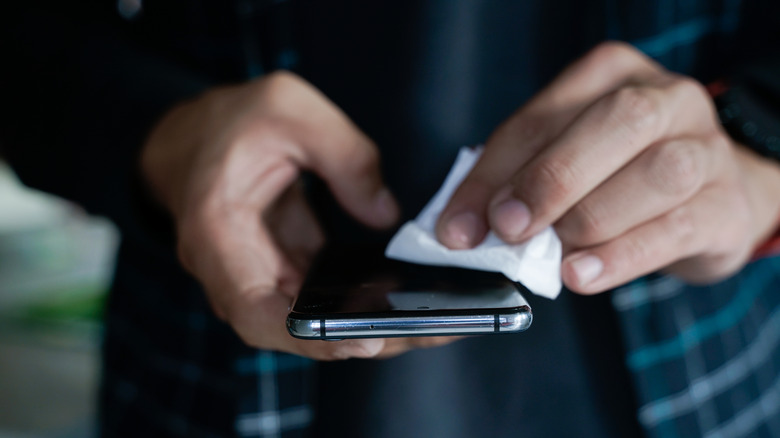 Hands wiping down a smartphone screen