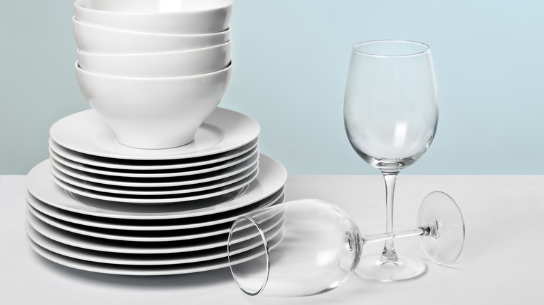 Stack of plates and bowls beside two wine glasses
