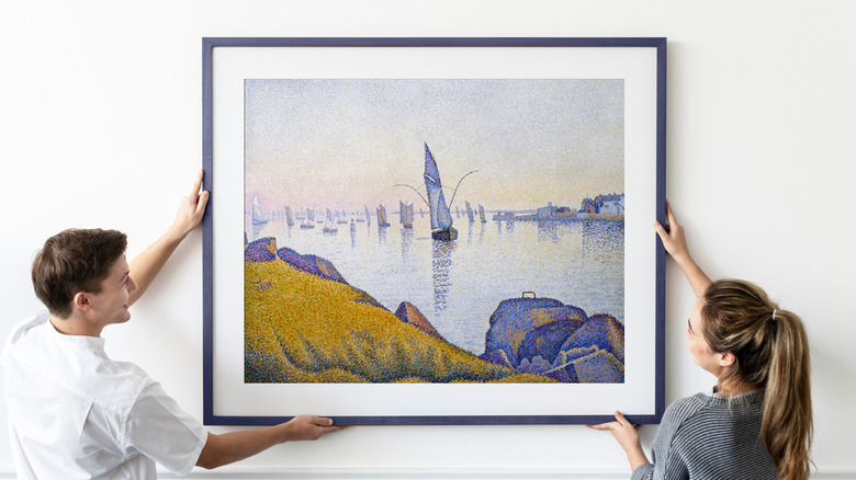 Couple hanging a framed painting on their wall