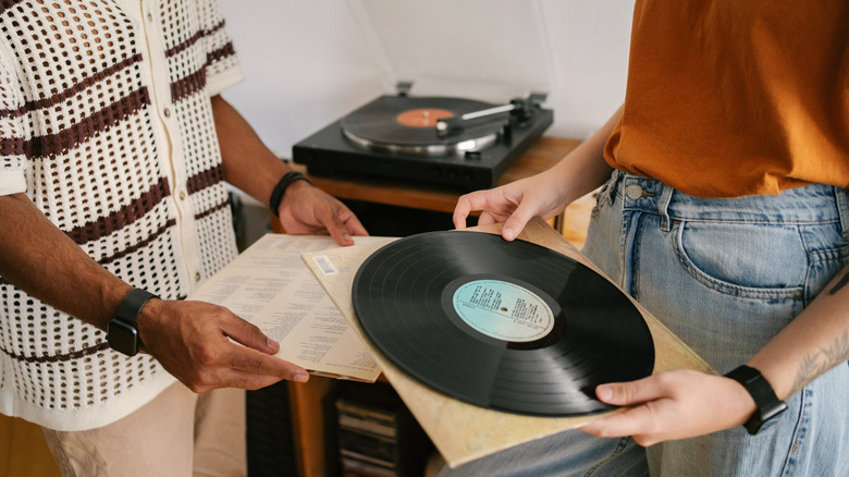 Two people holding vinyl records