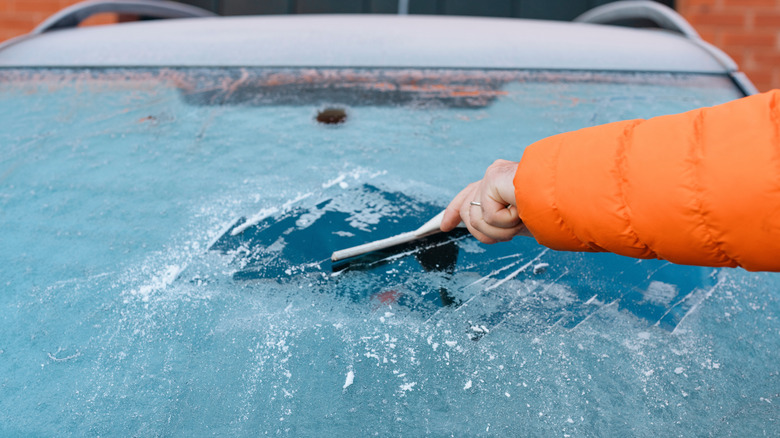 man scraping ice off a windshielf