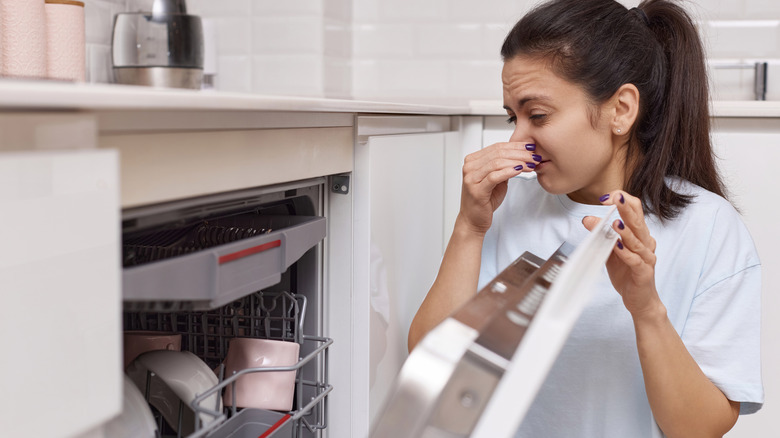 women holding nose to strange smell from dishwasher