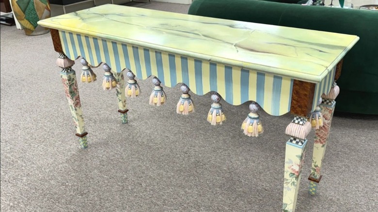 Mackenzie Childs painted side table sitting behind a sofa